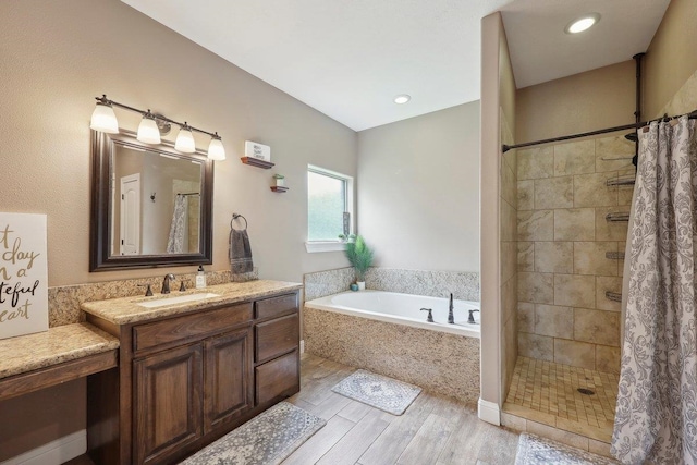 full bathroom featuring wood finished floors, a garden tub, a tile shower, and vanity