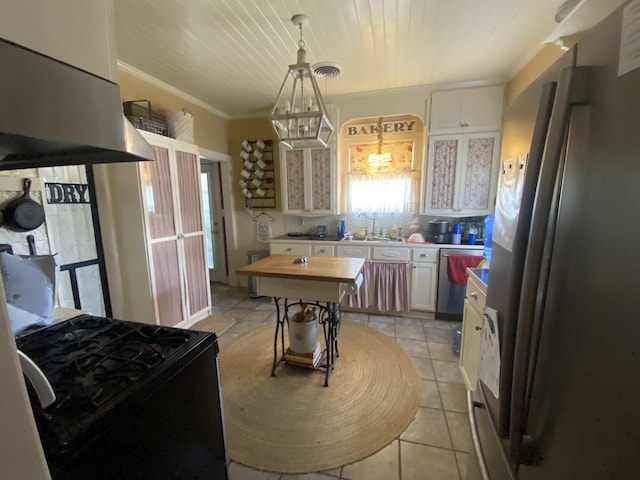 kitchen with appliances with stainless steel finishes, island range hood, white cabinets, butcher block countertops, and hanging light fixtures