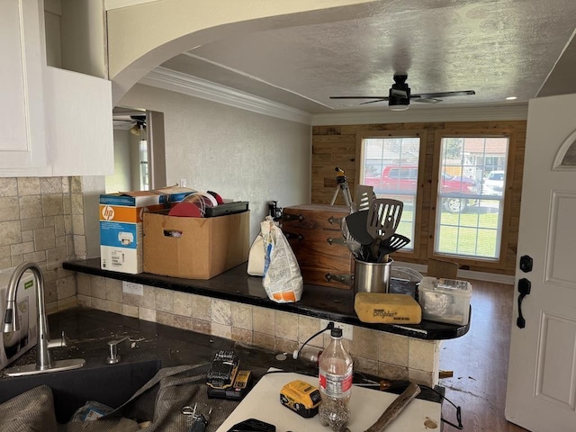 kitchen featuring arched walkways, crown molding, decorative backsplash, a ceiling fan, and a textured ceiling