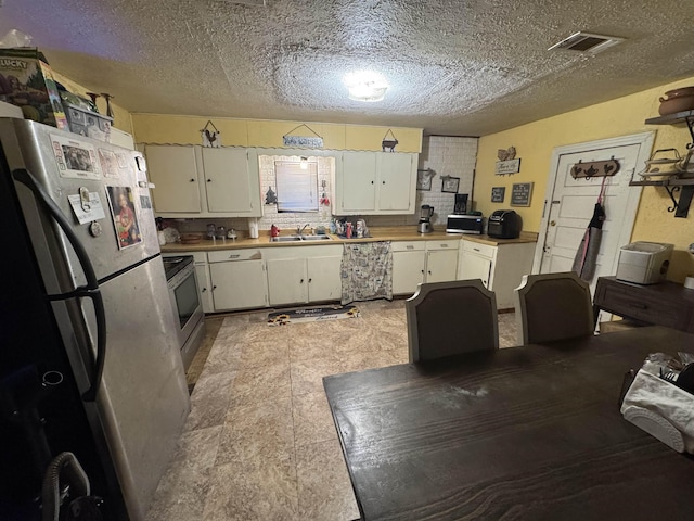 kitchen featuring visible vents, a sink, stainless steel appliances, light countertops, and white cabinets