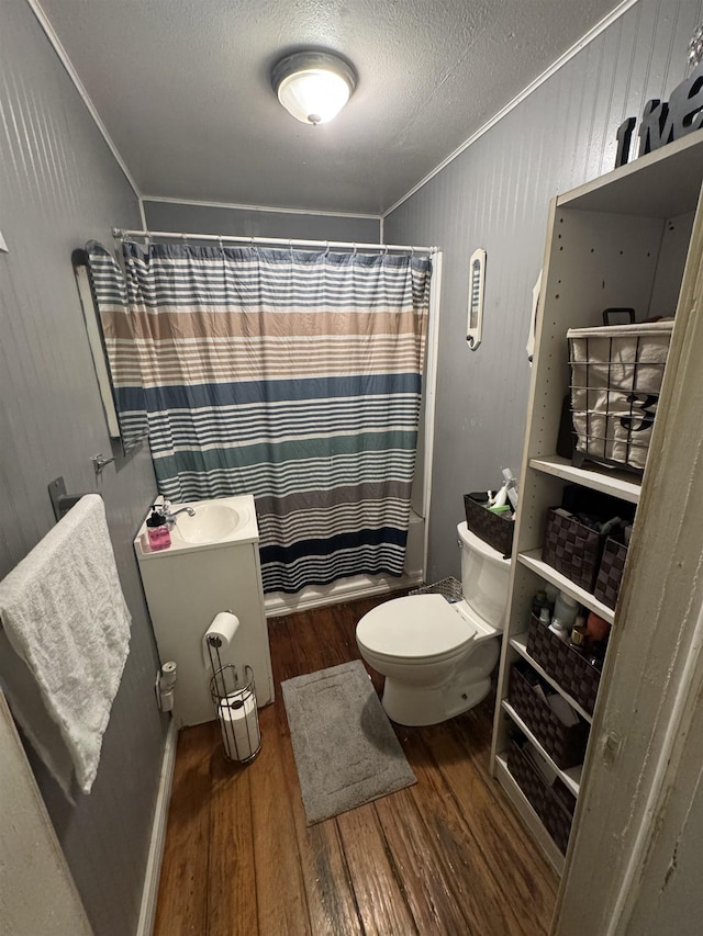 full bath featuring wood finished floors, a sink, ornamental molding, a textured ceiling, and toilet