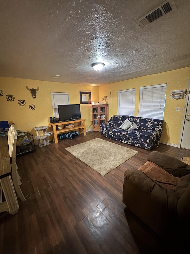 living room with visible vents, a textured ceiling, and wood finished floors