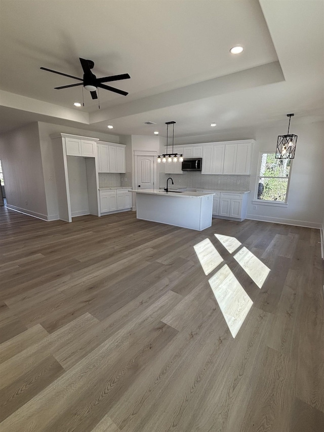 kitchen featuring white cabinetry, light hardwood / wood-style floors, a kitchen island with sink, and tasteful backsplash