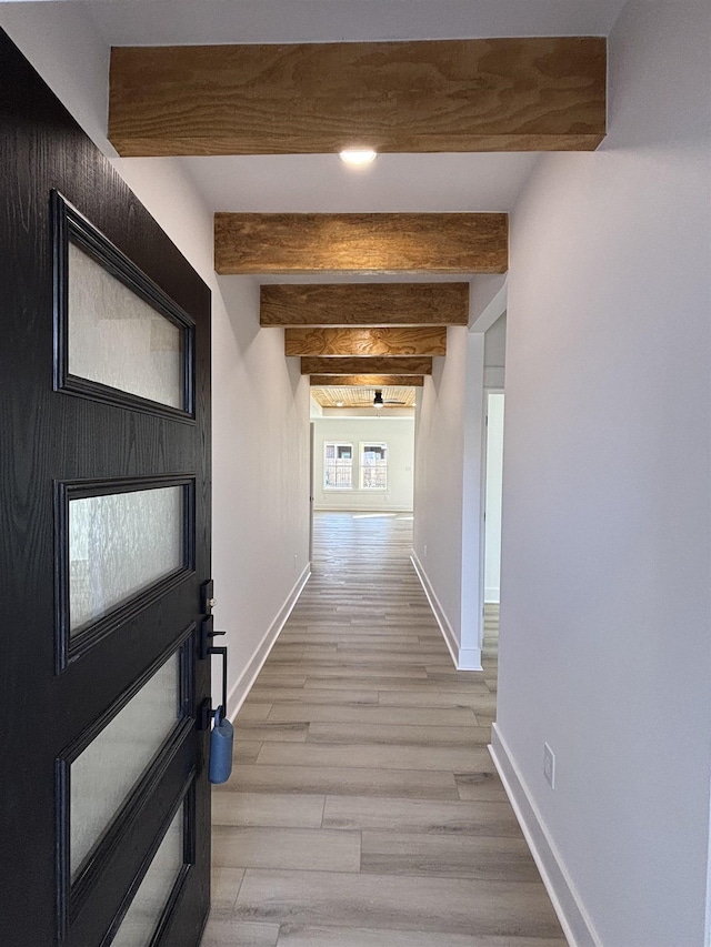 hallway featuring light hardwood / wood-style flooring and beamed ceiling