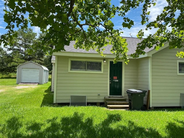 back of house with a lawn and a shed