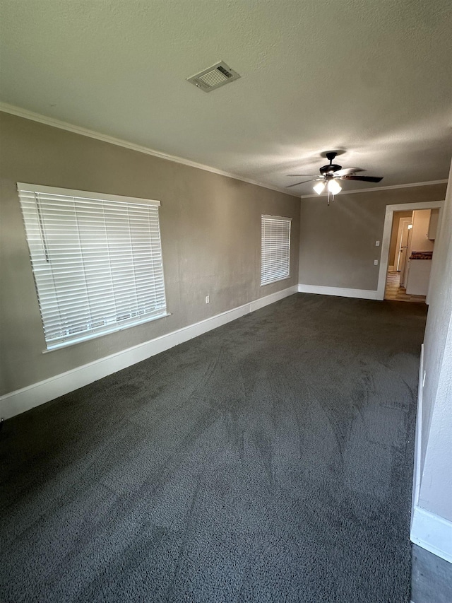 empty room with dark colored carpet, ceiling fan, ornamental molding, and a textured ceiling