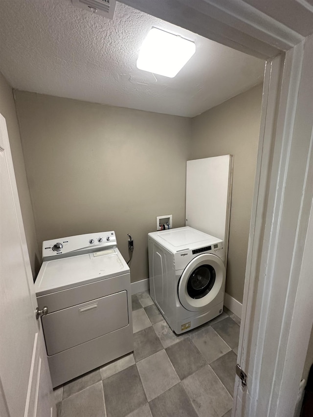 clothes washing area with a textured ceiling and washer and clothes dryer