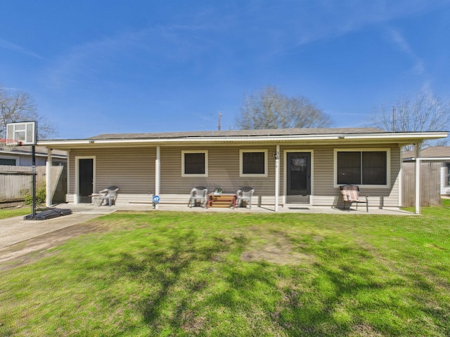 rear view of property featuring a patio, a lawn, and fence