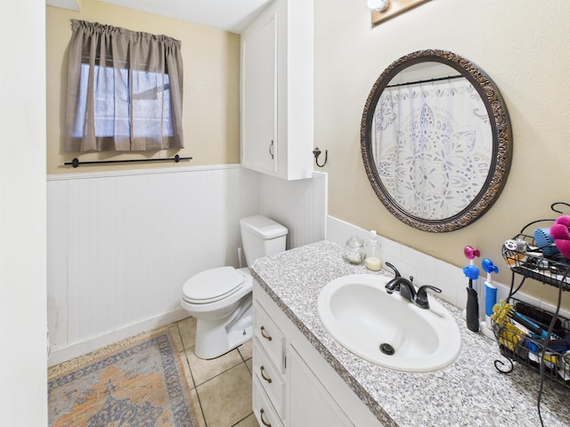 bathroom with tile patterned flooring, a wainscoted wall, vanity, and toilet