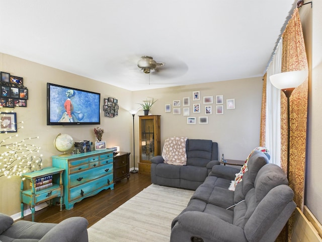 living area with ceiling fan, dark wood-type flooring, and baseboards