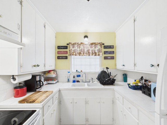 kitchen with range with electric cooktop, a sink, white cabinetry, tile counters, and tasteful backsplash