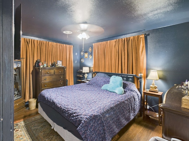 bedroom featuring a textured ceiling, a ceiling fan, wood finished floors, and a textured wall