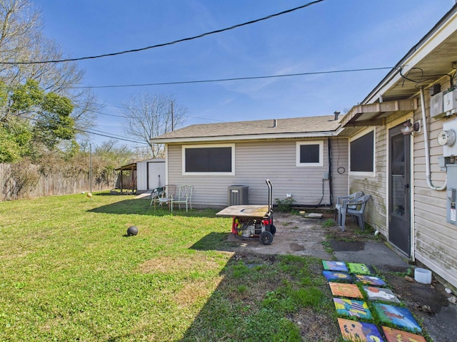 rear view of house with an outbuilding, a patio, a lawn, a storage shed, and fence