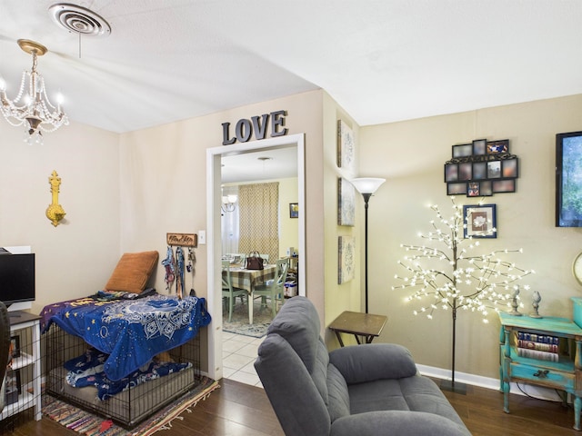 bedroom featuring baseboards, visible vents, an inviting chandelier, and wood finished floors