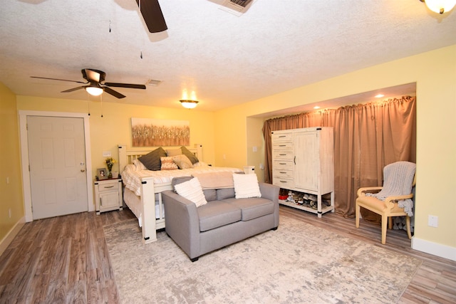 bedroom with a textured ceiling, ceiling fan, and light hardwood / wood-style flooring