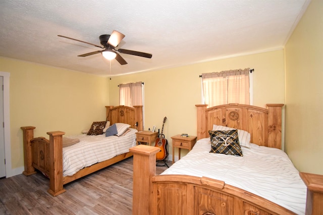 bedroom with multiple windows, ceiling fan, hardwood / wood-style floors, and a textured ceiling