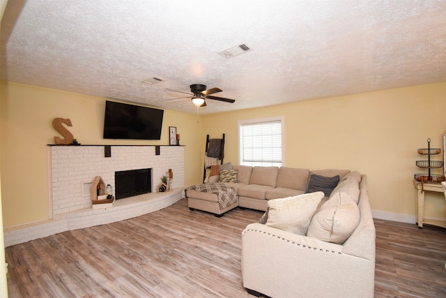 living room featuring hardwood / wood-style flooring, a fireplace, a textured ceiling, and ceiling fan