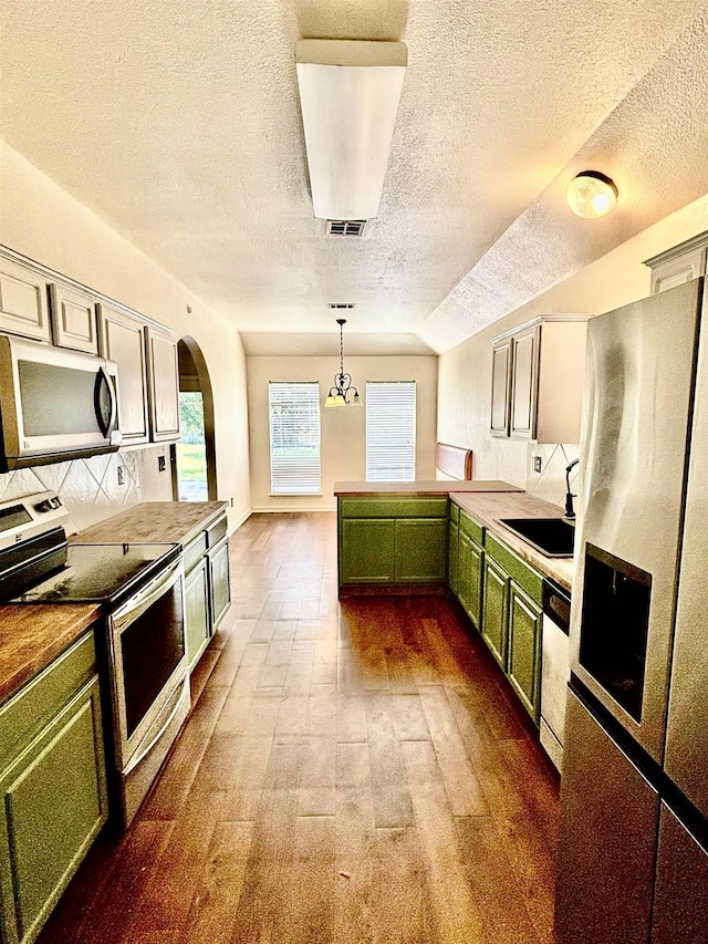 kitchen featuring sink, green cabinetry, a textured ceiling, decorative light fixtures, and stainless steel appliances