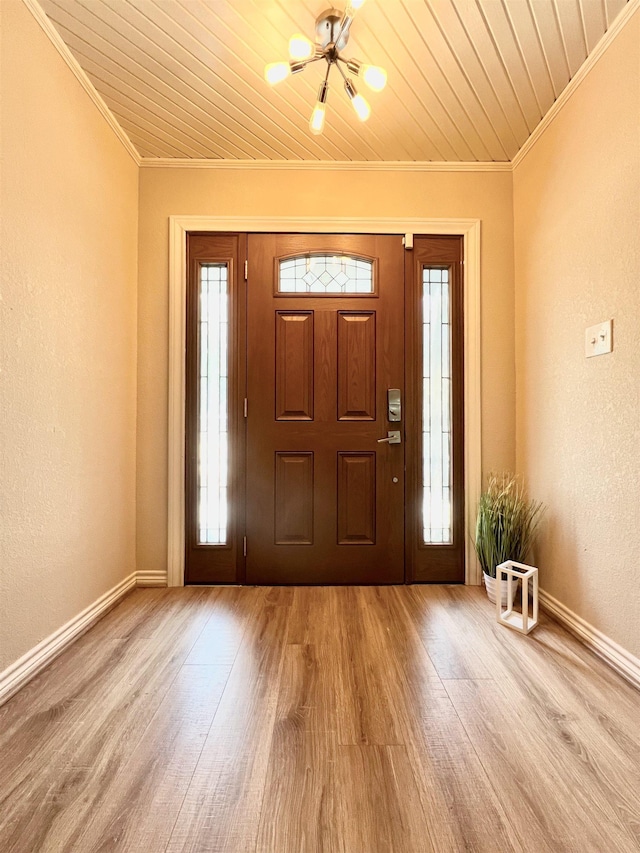 foyer entrance with light hardwood / wood-style floors, ornamental molding, a wealth of natural light, and a chandelier