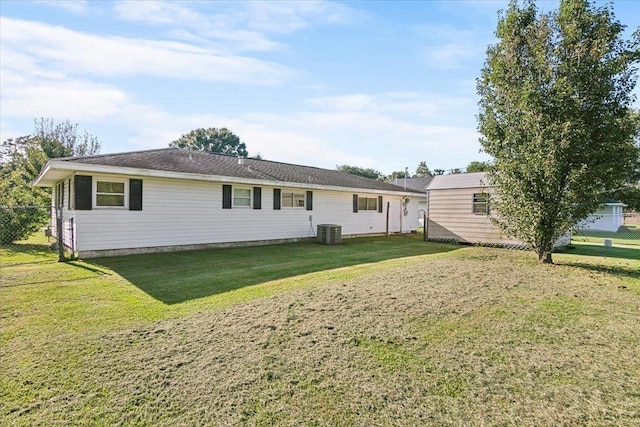 rear view of house featuring cooling unit and a yard