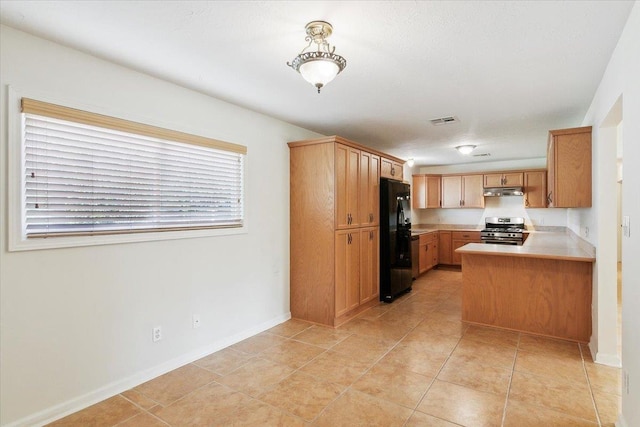 kitchen with kitchen peninsula, black refrigerator, light tile patterned floors, and stainless steel range with gas stovetop