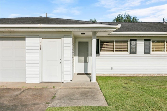 doorway to property with a yard and a garage