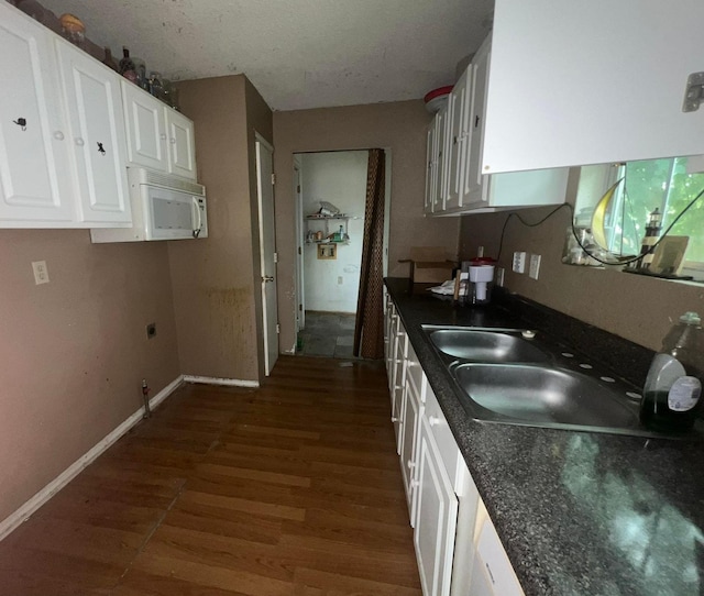 2007 Queen Ave, Nederland, TX 77627 - kitchen featuring white microwave, dark wood finished floors, dark countertops, and white cabinets