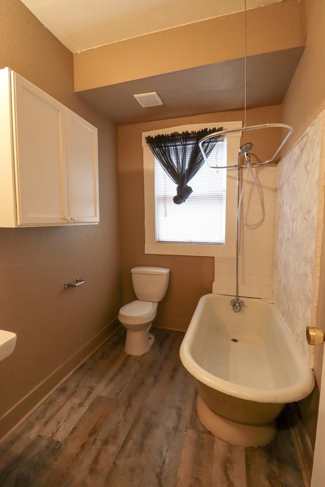 bathroom featuring hardwood / wood-style flooring, bathtub / shower combination, and toilet