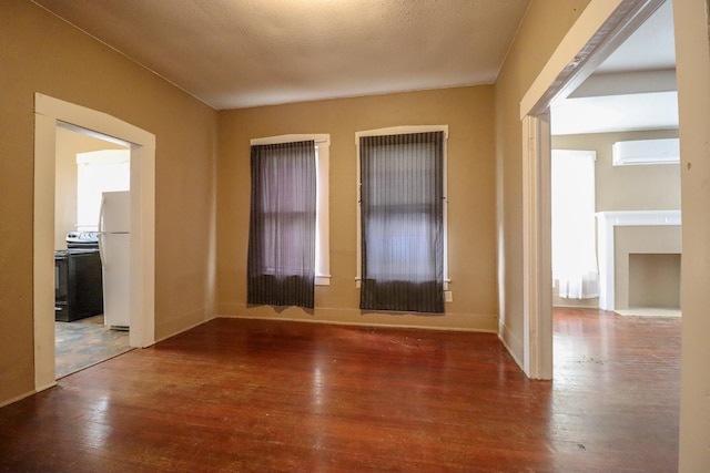 spare room with wood-type flooring, a wall unit AC, and a textured ceiling