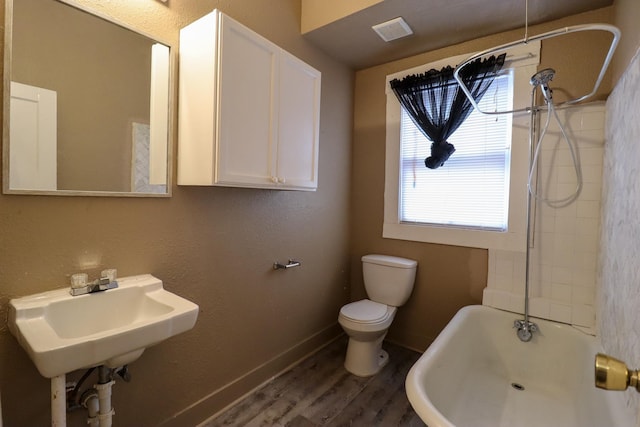 bathroom featuring hardwood / wood-style flooring, toilet, and a bath