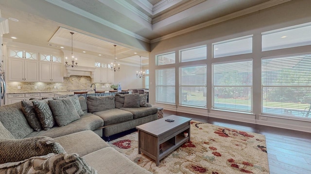 6570 Merrick Ln, Beaumont, TX 77706 - living room with a chandelier, light wood finished floors, crown molding, healthy amount of natural light, and a raised ceiling