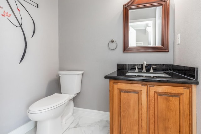 bathroom with marble finish floor, toilet, vanity, and baseboards