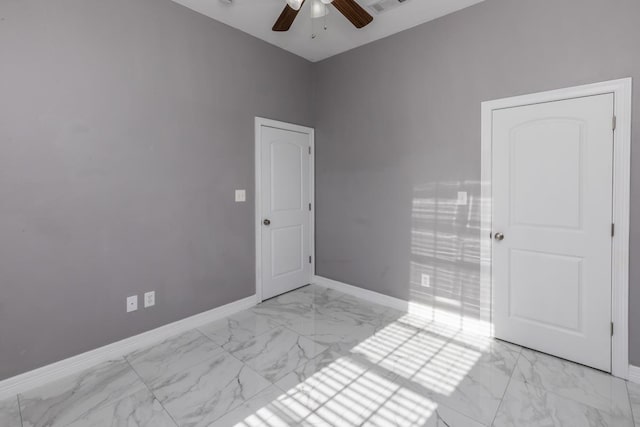 spare room featuring marble finish floor, baseboards, and a ceiling fan