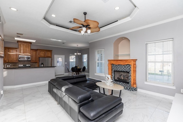 living area featuring baseboards, a raised ceiling, a wealth of natural light, and crown molding