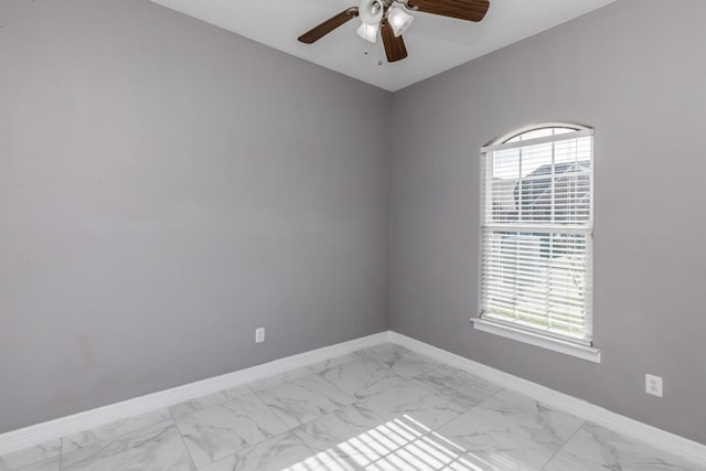 empty room with marble finish floor, ceiling fan, and baseboards