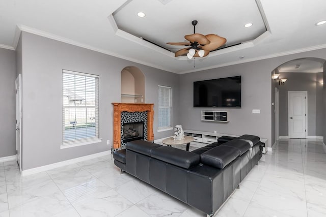 living area with arched walkways, a fireplace, a raised ceiling, and baseboards