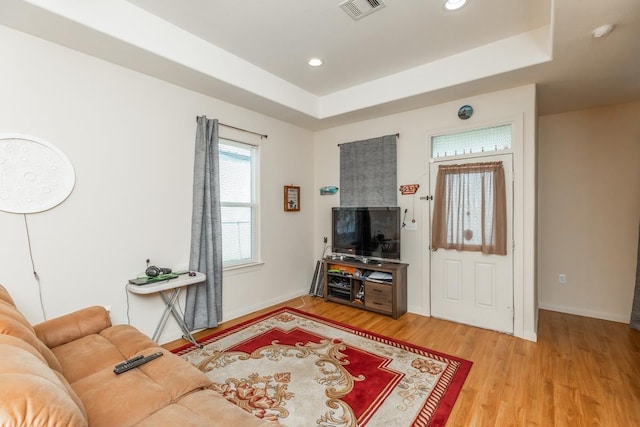 living room with a raised ceiling and hardwood / wood-style floors