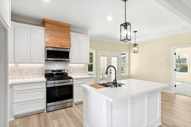 kitchen featuring a kitchen island with sink, sink, stainless steel appliances, and white cabinets