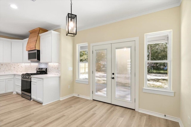 kitchen with pendant lighting, backsplash, stainless steel appliances, and white cabinets