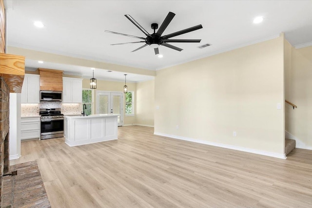 kitchen with appliances with stainless steel finishes, white cabinetry, hanging light fixtures, backsplash, and light hardwood / wood-style floors