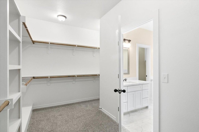 walk in closet with sink and light carpet