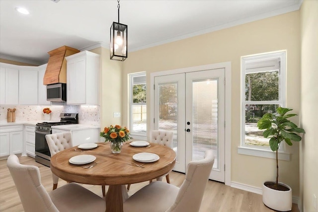 dining area featuring crown molding, light hardwood / wood-style flooring, and french doors