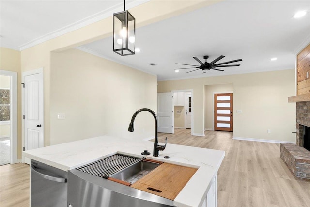 kitchen featuring a fireplace, dishwasher, sink, hanging light fixtures, and crown molding