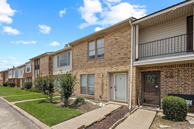 1003 Park Mdw, Beaumont, TX 77706 - townhome / multi-family property with a balcony, brick siding, a front lawn, and a residential view