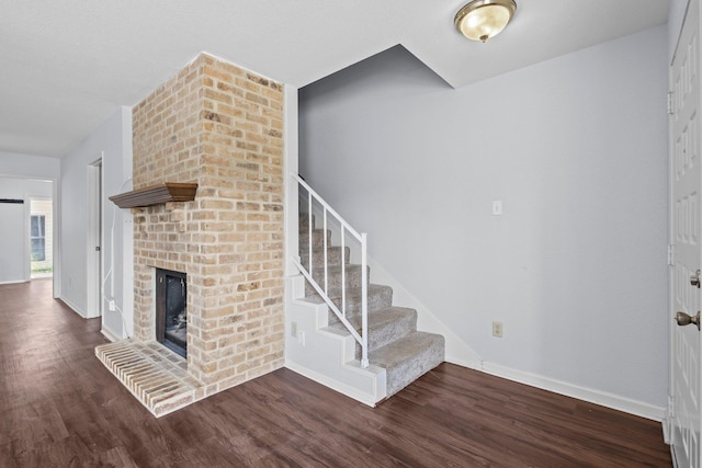 1003 Park Mdw, Beaumont, TX 77706 - unfurnished living room with wood finished floors, baseboards, a brick fireplace, and stairway