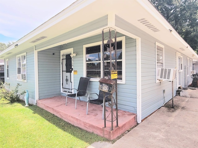 2210 Nora St, Beaumont, TX 77705 - view of exterior entry with covered porch, cooling unit, and a lawn