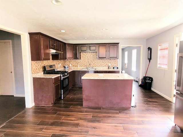 2210 Nora St, Beaumont, TX 77705 - kitchen featuring stainless steel range with gas stovetop, under cabinet range hood, dark wood finished floors, dark brown cabinetry, and recessed lighting