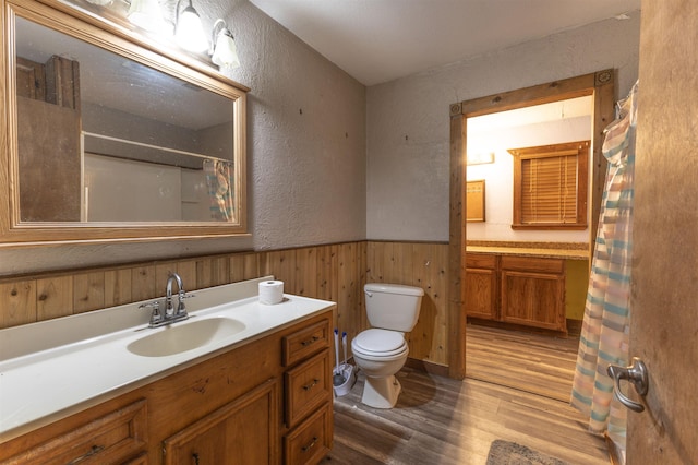 bathroom featuring vanity, hardwood / wood-style floors, toilet, and wood walls