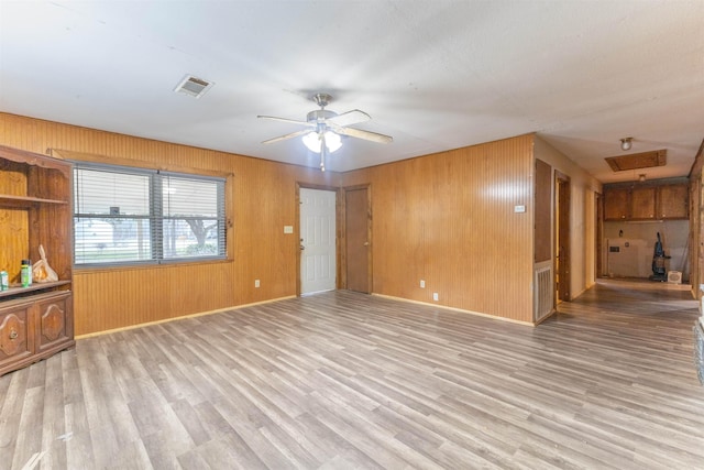 unfurnished living room featuring light hardwood / wood-style flooring, wooden walls, and ceiling fan