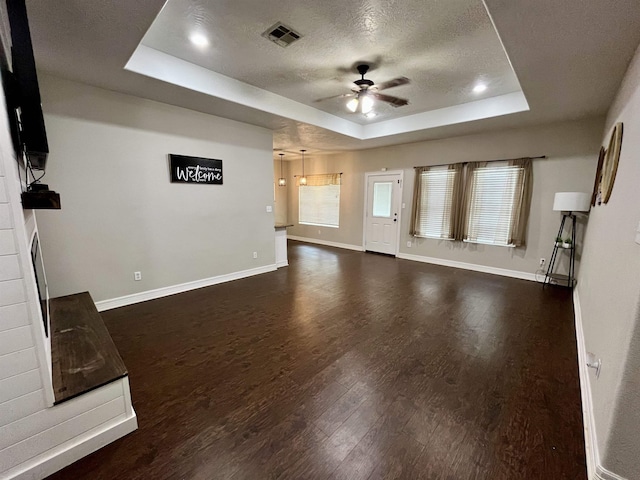 479 Reynolds Ln, Vidor, TX 77662 - unfurnished living room featuring ceiling fan, a textured ceiling, visible vents, a raised ceiling, and dark wood-style floors
